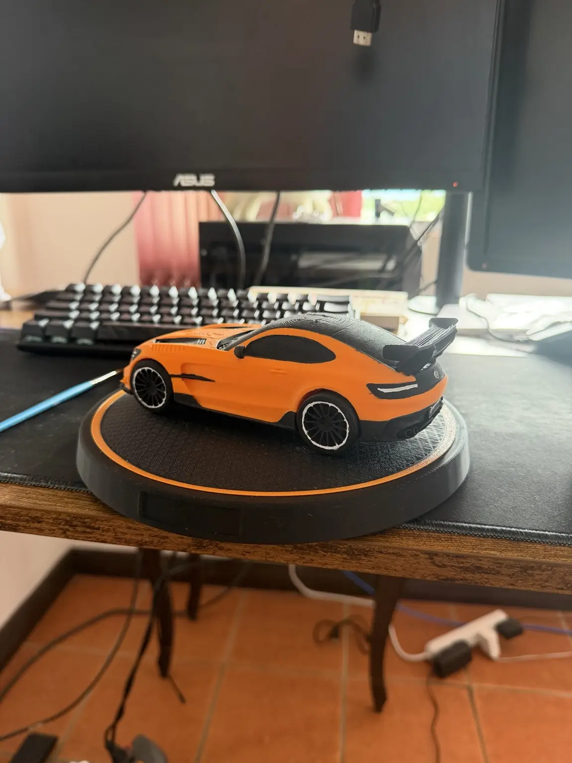 Vista lateral del modelo decorativo naranja terminado con ruedas y detalles negros
