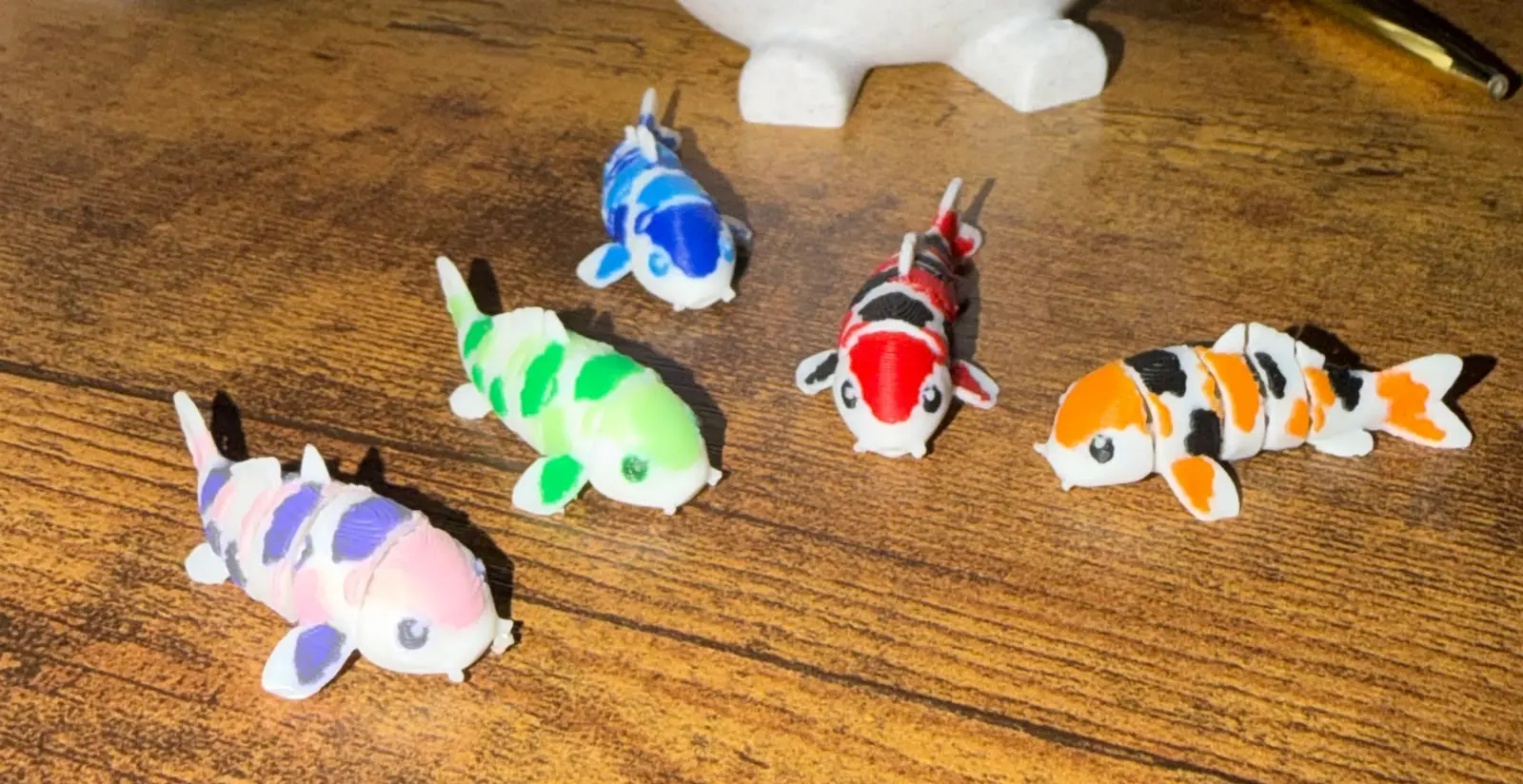 Cinco muestras físicas de peces koi impresos en varias combinaciones de color sobre una mesa